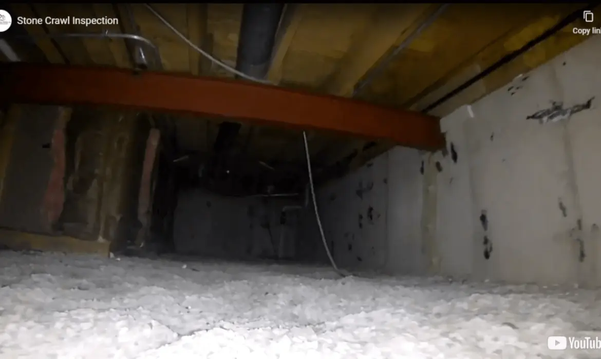 Compact crawlspace inspection robot navigating under a house with stone foundation for home inspection