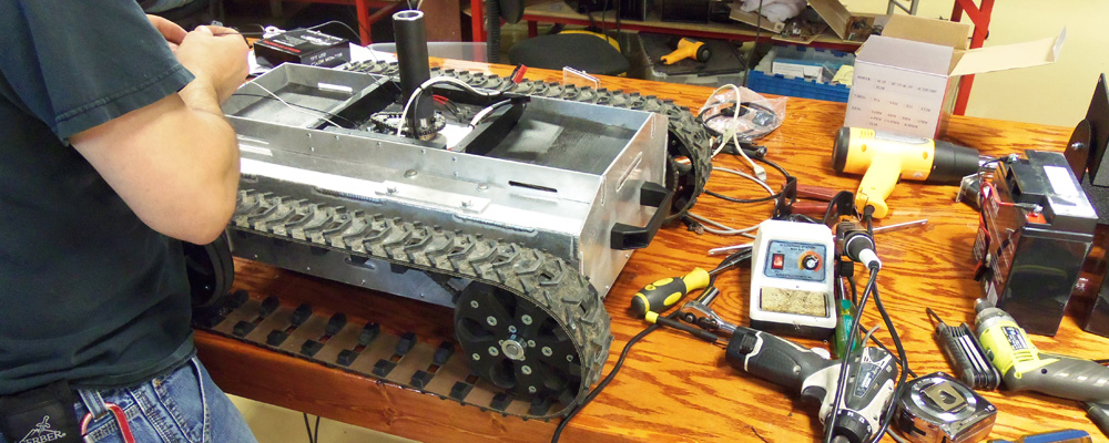 Hands assembling a SuperDroid robot chassis